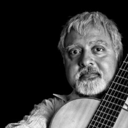 Image of Fareed Haque holding an acoustic guitar.